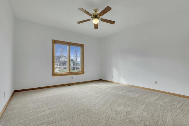 spare room with baseboards, visible vents, a ceiling fan, and light colored carpet