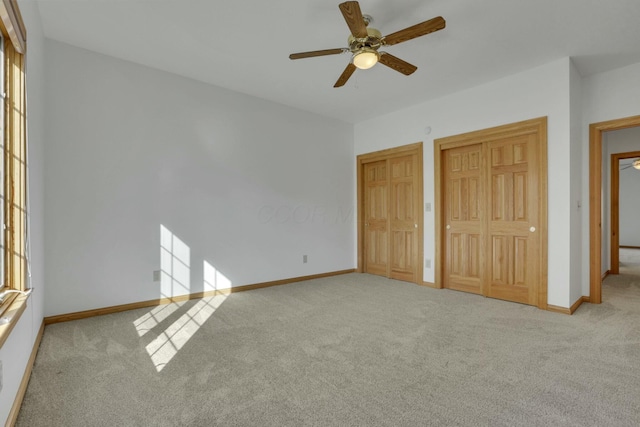 unfurnished bedroom with multiple closets, carpet, ceiling fan, and baseboards