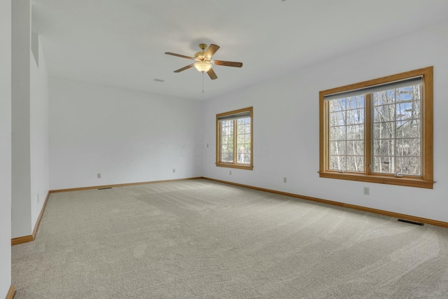 carpeted spare room with ceiling fan, visible vents, and baseboards