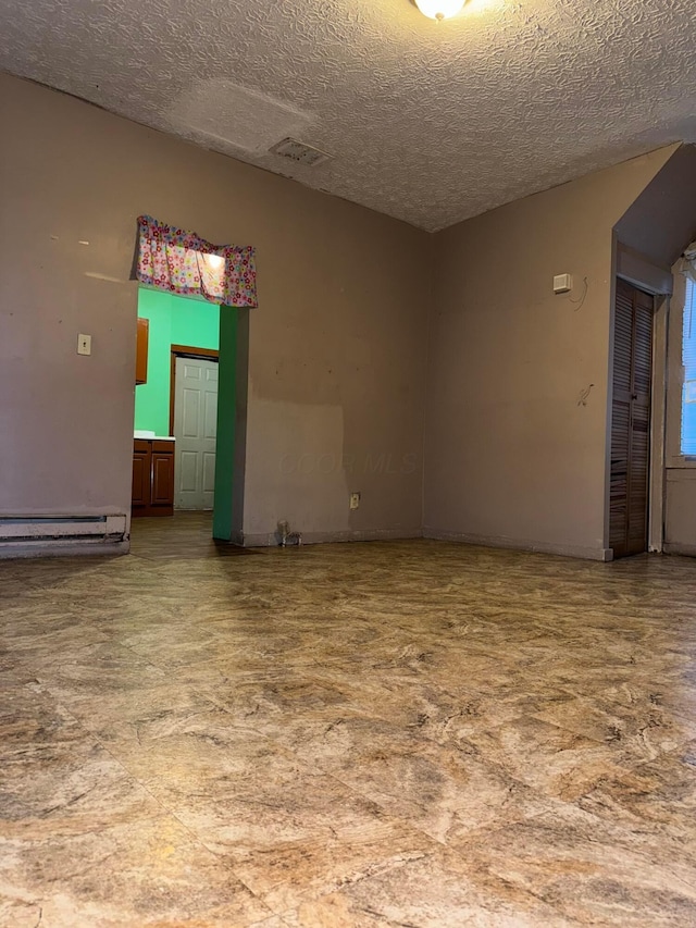 empty room featuring a baseboard radiator and a textured ceiling