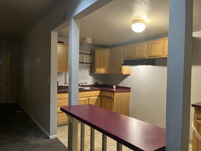 kitchen featuring light brown cabinets, a textured ceiling, light tile patterned floors, and sink