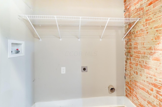 clothes washing area with washer hookup, electric dryer hookup, and brick wall