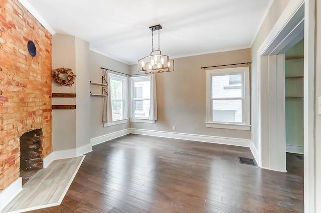 unfurnished dining area with a notable chandelier, ornamental molding, dark wood-type flooring, and a wealth of natural light