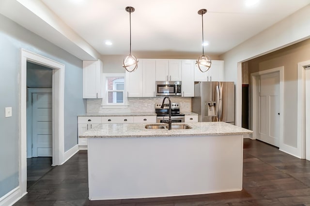 kitchen with appliances with stainless steel finishes, white cabinetry, pendant lighting, and light stone counters