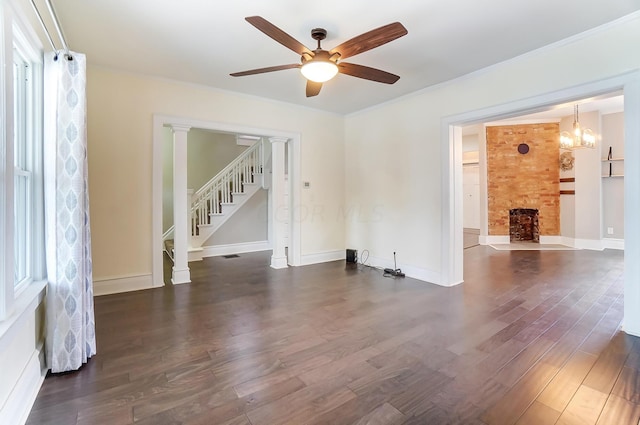 empty room featuring a fireplace, crown molding, dark wood-type flooring, and ceiling fan with notable chandelier