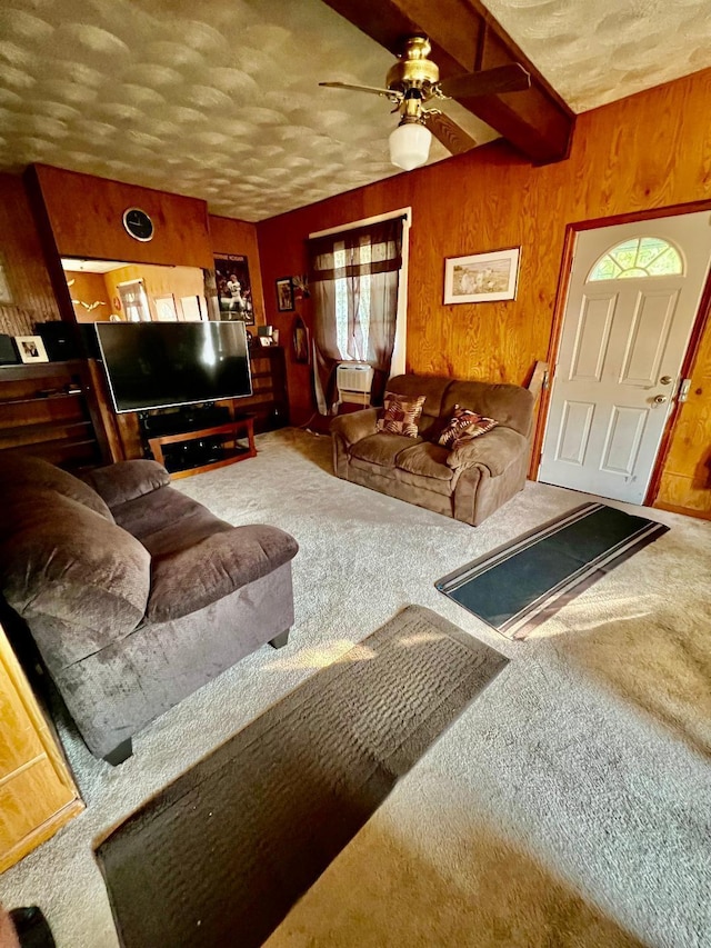 living room with beam ceiling, wooden walls, carpet floors, and ceiling fan