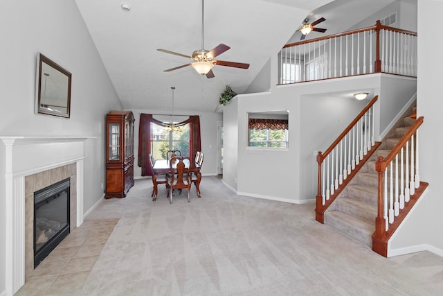 carpeted living room featuring ceiling fan, high vaulted ceiling, and a tiled fireplace