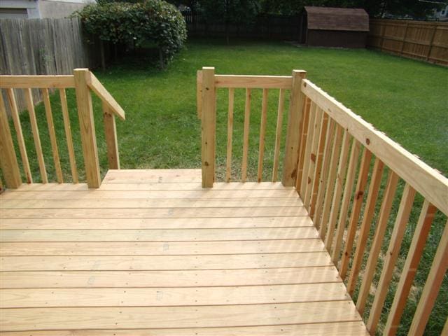 wooden terrace with a storage unit and a lawn