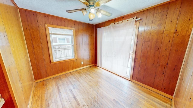 unfurnished bedroom with light wood-type flooring, ceiling fan, and wooden walls