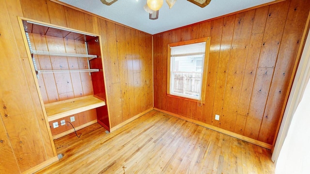 unfurnished bedroom with wood-type flooring, wood walls, and ceiling fan