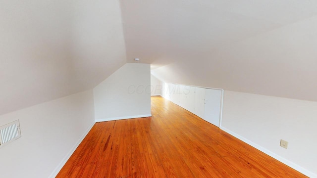 bonus room with lofted ceiling and light wood-type flooring