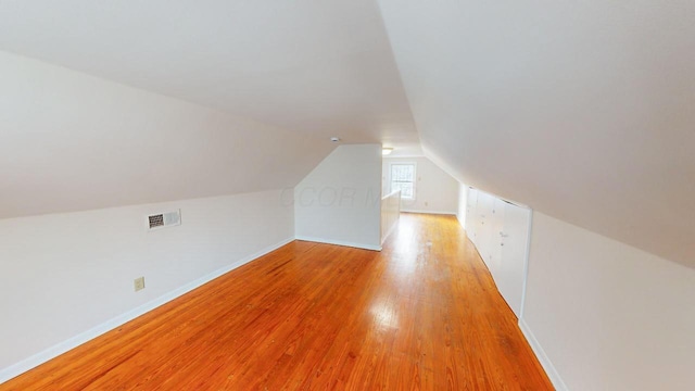 additional living space with light wood-type flooring and vaulted ceiling