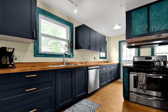 kitchen featuring butcher block counters, a wealth of natural light, stainless steel appliances, and ventilation hood