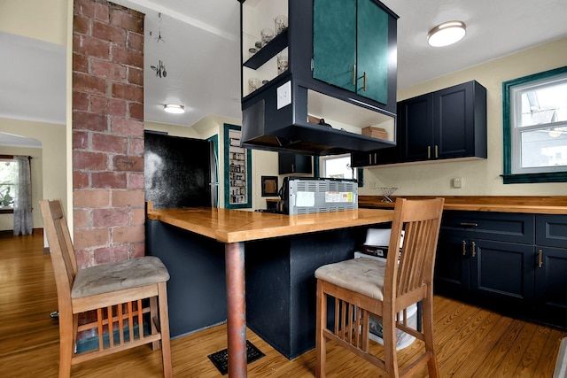 kitchen featuring butcher block counters, crown molding, light hardwood / wood-style flooring, and blue cabinets