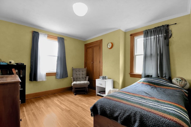 bedroom featuring light hardwood / wood-style floors, crown molding, and multiple windows