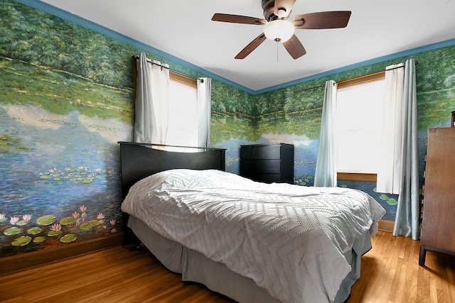 bedroom featuring ceiling fan, light hardwood / wood-style floors, ornamental molding, and multiple windows