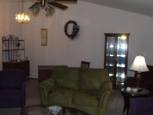 living room featuring ceiling fan with notable chandelier and vaulted ceiling