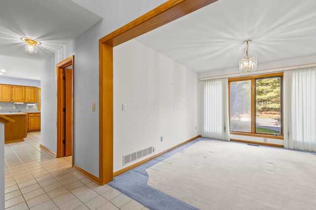 carpeted empty room featuring a chandelier