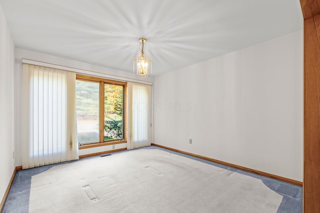 spare room featuring carpet and an inviting chandelier