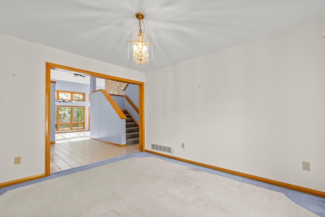 carpeted spare room with ceiling fan with notable chandelier