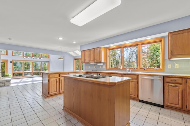 kitchen with appliances with stainless steel finishes, tasteful backsplash, sink, decorative light fixtures, and a kitchen island