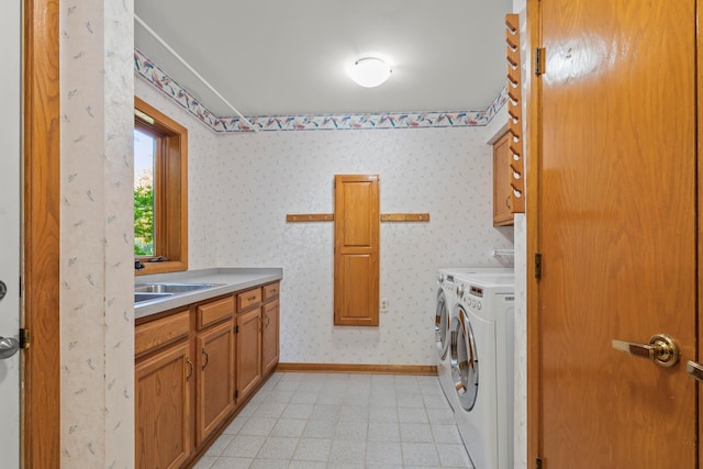 clothes washing area with washer and dryer, sink, light tile patterned flooring, and cabinets