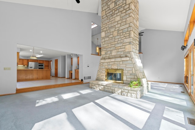 unfurnished living room with ceiling fan, a fireplace, and high vaulted ceiling