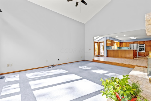 unfurnished living room featuring light carpet, high vaulted ceiling, and ceiling fan