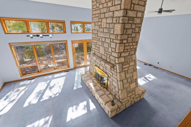 carpeted living room with a fireplace, a high ceiling, and ceiling fan