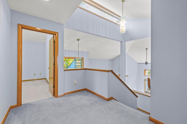 carpeted empty room with a chandelier and vaulted ceiling