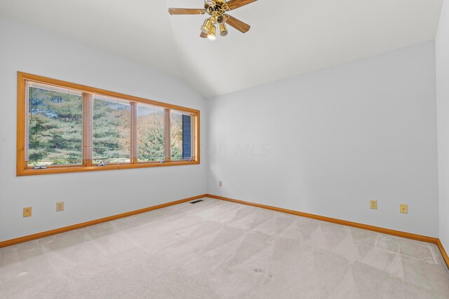 empty room with light colored carpet, vaulted ceiling, and ceiling fan