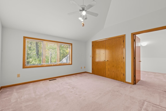 unfurnished bedroom with ceiling fan, a closet, light colored carpet, and lofted ceiling