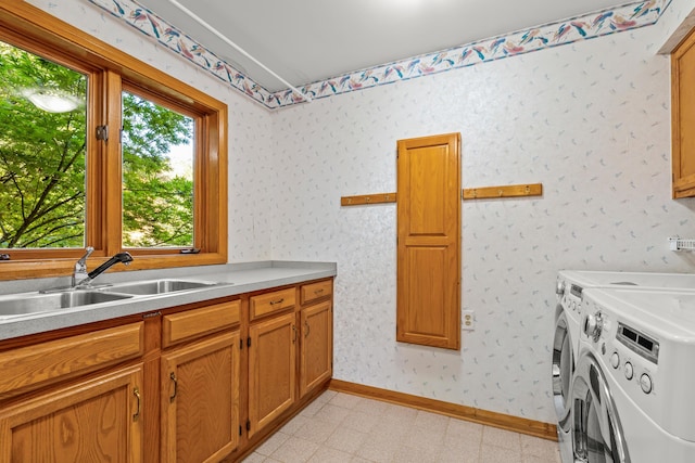 clothes washing area with cabinets, sink, and washing machine and clothes dryer