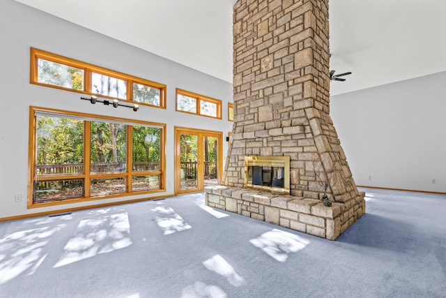 unfurnished living room featuring a fireplace, carpet, a towering ceiling, and ceiling fan