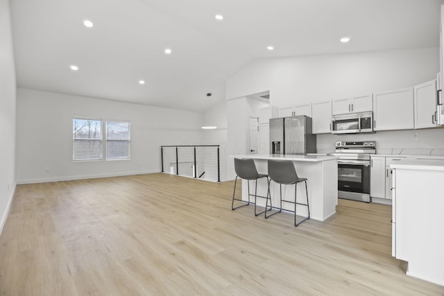 kitchen with light wood-type flooring, a breakfast bar, stainless steel appliances, a center island, and white cabinetry