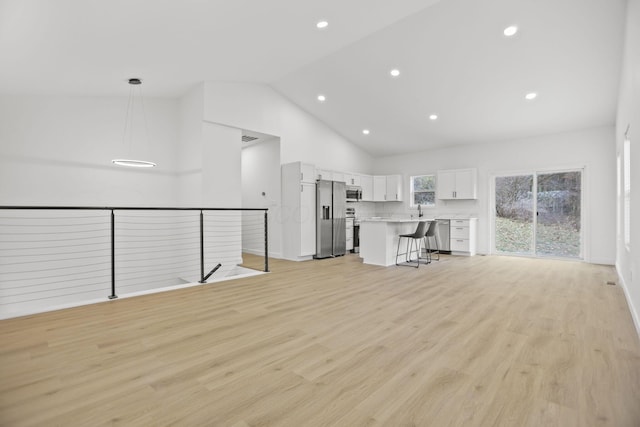 unfurnished living room featuring sink, high vaulted ceiling, and light hardwood / wood-style flooring