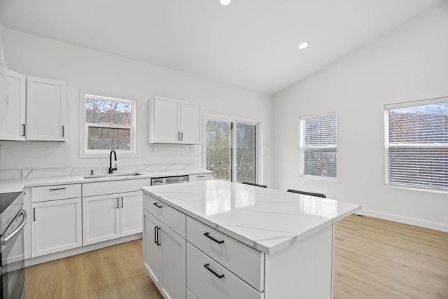 kitchen with light wood-type flooring, a center island, white cabinetry, and sink