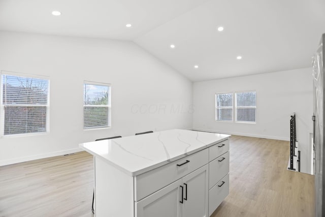 kitchen with plenty of natural light, a kitchen island, lofted ceiling, and light wood-type flooring