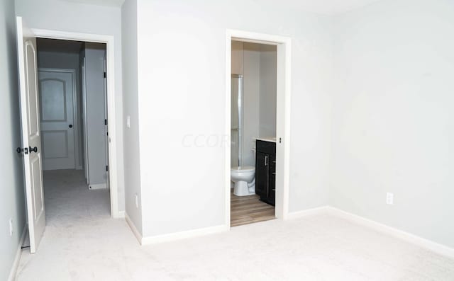 unfurnished bedroom with light carpet and connected bathroom