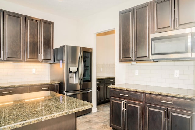 kitchen featuring dark brown cabinetry, decorative backsplash, stainless steel appliances, and stone countertops