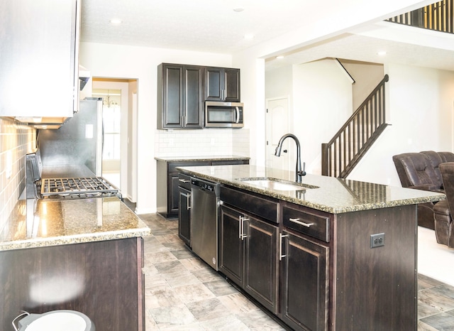 kitchen featuring appliances with stainless steel finishes, backsplash, a center island with sink, and sink