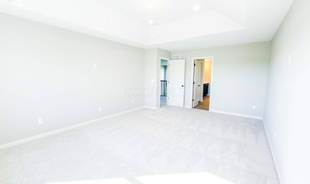 carpeted empty room featuring a raised ceiling