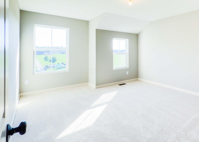 spare room featuring light carpet and lofted ceiling