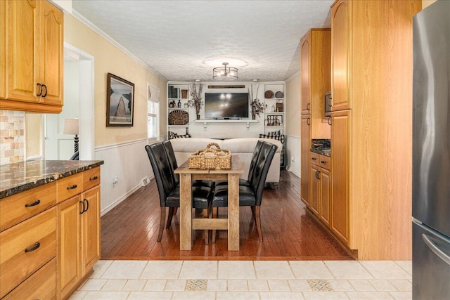 dining space with light hardwood / wood-style floors, ornamental molding, and a textured ceiling