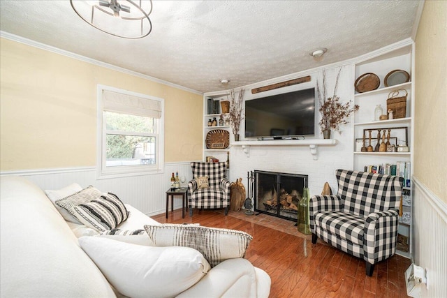 living room with hardwood / wood-style floors, a textured ceiling, and a brick fireplace