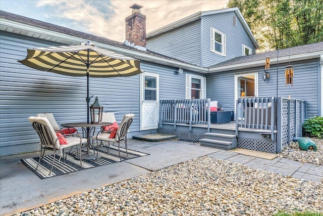 rear view of house featuring a wooden deck and a patio area