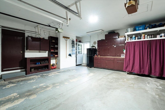 garage with a garage door opener, a workshop area, and black fridge