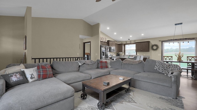 living room featuring ceiling fan, sink, vaulted ceiling, and hardwood / wood-style flooring