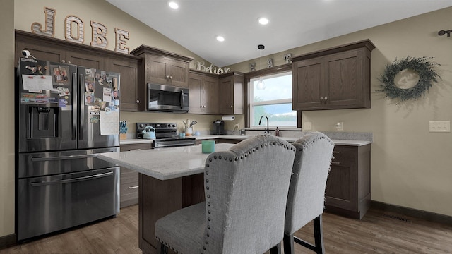 kitchen with appliances with stainless steel finishes, dark hardwood / wood-style floors, vaulted ceiling, and pendant lighting