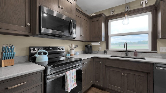 kitchen with hanging light fixtures, dark brown cabinetry, sink, and appliances with stainless steel finishes